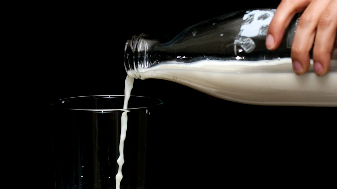 Person pouring milk in glass