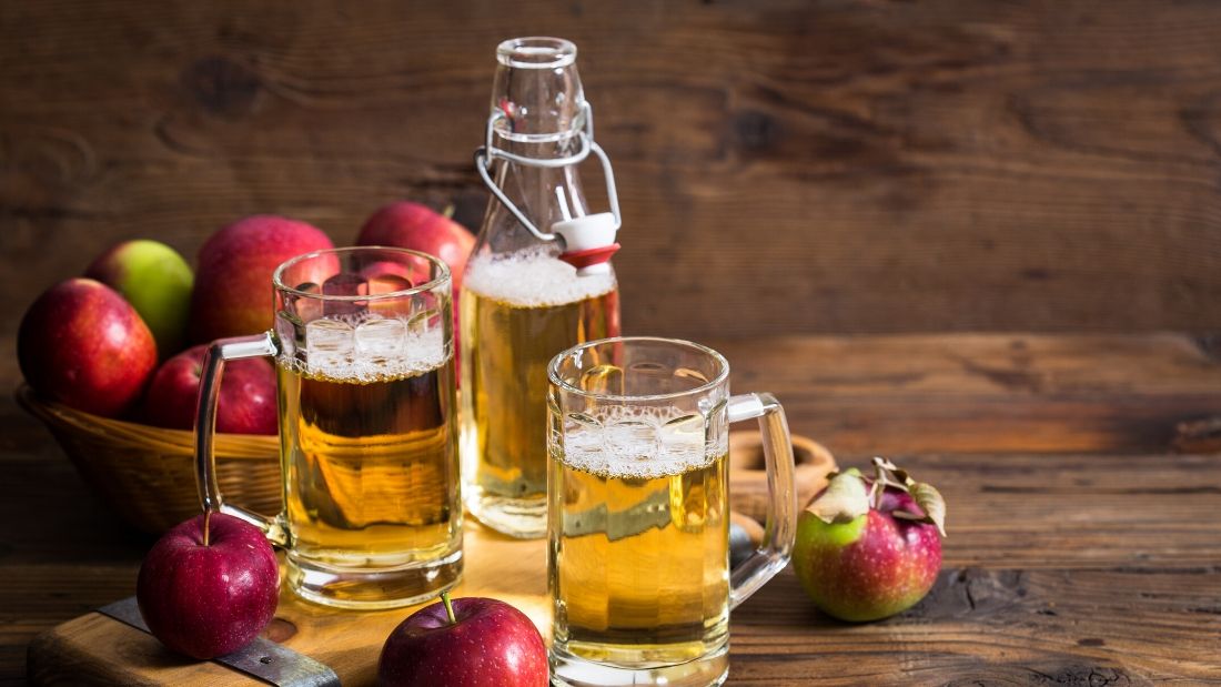 pints of vegan cider on table surrounded by apples