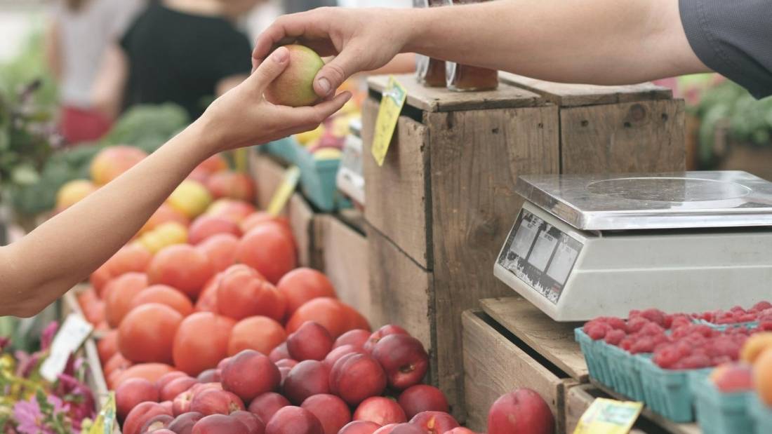 consumer behaviour person handing someone piece of fruit