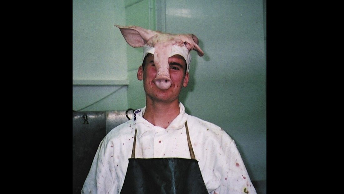 slaughterhouse worker wearing the top of a pigs head on his head like a hat