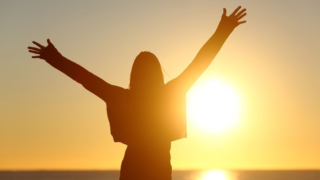 person holding their arms out to the sun