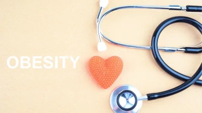 Stethoscope and a toy heart and the word obesity